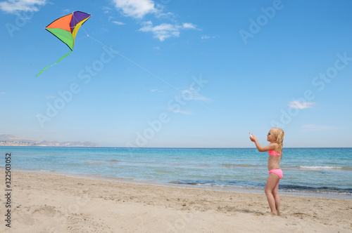 Little happy girl playing with flying kite. Summer vacation concept