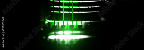 Electric guitar with green lights. Neck and fingerboard of musical instrument. Creative style photo with shadows.