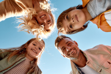 Our family is the best. Bottom view of happy and positive family smiling at camera while standing outdoors