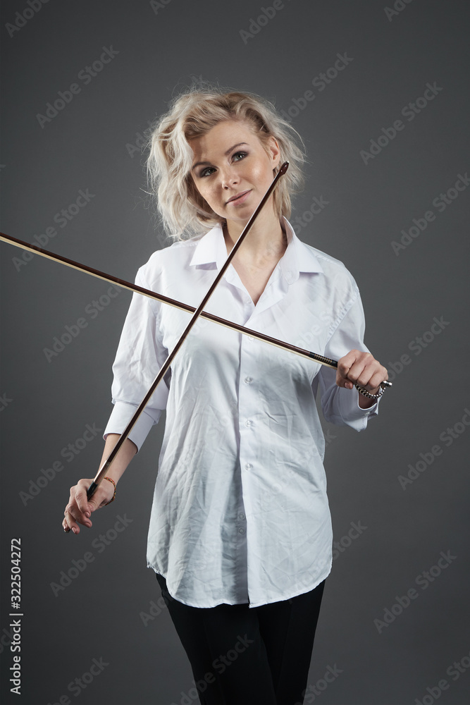 Young blonde caucasian girl violinist posing holding two violin bows