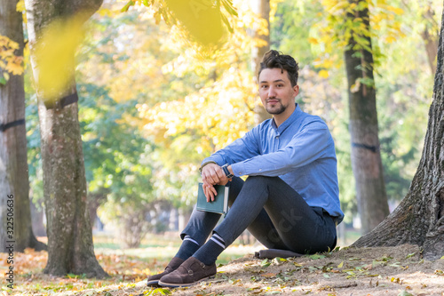 Obraz na płótnie Handsome young man looking at the camera. Portrait of a confident and successful young man with a denim jacket and blue shirt outside. Happy guy smiling w salonie