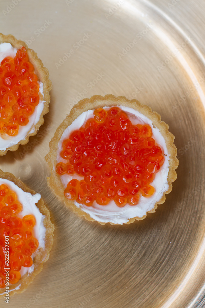 three tartlets with cream cheese and red caviar on a gold plate. the concept of a delicious Breakfast, buffet and snack. seafood dish. the view from the top. space for text. three tartlets with cream cheese and red caviar on a gold plate. the concept of a delicious Breakfast, buffet and snack. seafood dish. the view from the top. space for text.