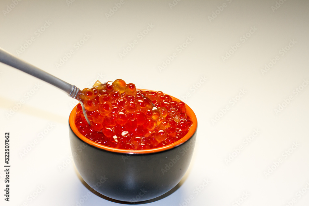 red caviar in a saucer with a spoon on a light table. the concept of a delicious Breakfast, buffet and snack. seafood dish. the view from the top. space for text. red caviar in a saucer with a spoon on a light table. the concept of a delicious Breakfast, buffet and snack. seafood dish. the view from the top. space for text.