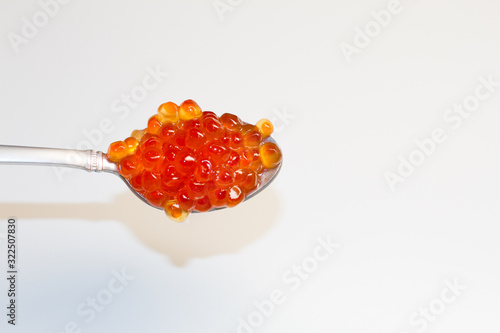 red caviar in a saucer with a spoon on a light table. the concept of a delicious Breakfast, buffet and snack. seafood dish. the view from the top. space for text.