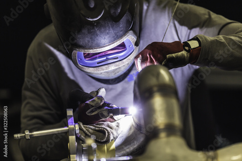 Welder industrial worker welding with argon machine