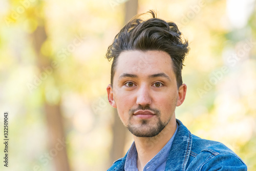 Portrait of a confident and successful young man with a denim jacket and blue shirt outside. Handsome young man outside