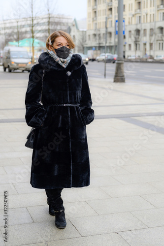 young european woman in protective disposable medical black mask in city outdoor. concept protection of dangerous 2019-nCoV influenza coronavirus, mutated and spreading in China. vertical photo