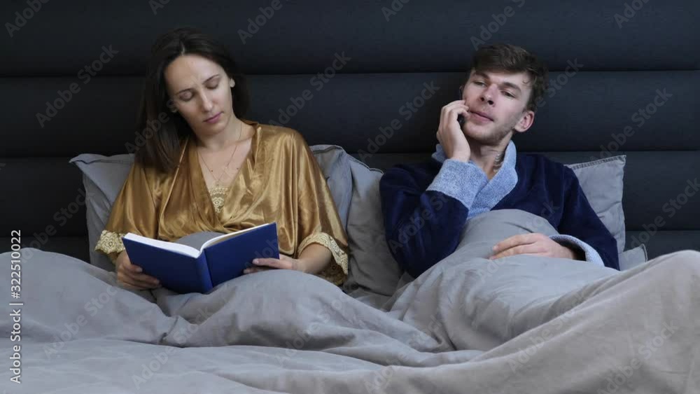 Female and male lying in bed before sleeping. Young family couple lies ...