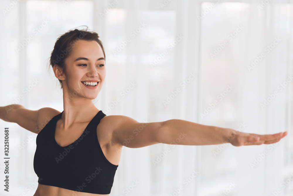 Woman exercising yoga in warrior pose in modern studio