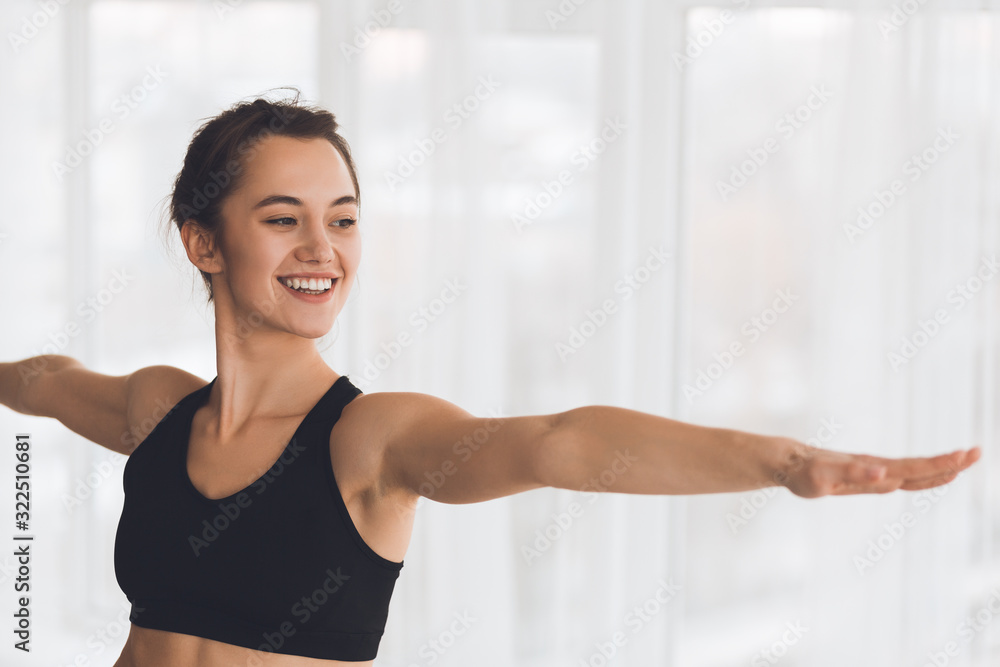 Woman exercising yoga in warrior pose in modern studio Woman exercising yoga in warrior pose in modern studio
