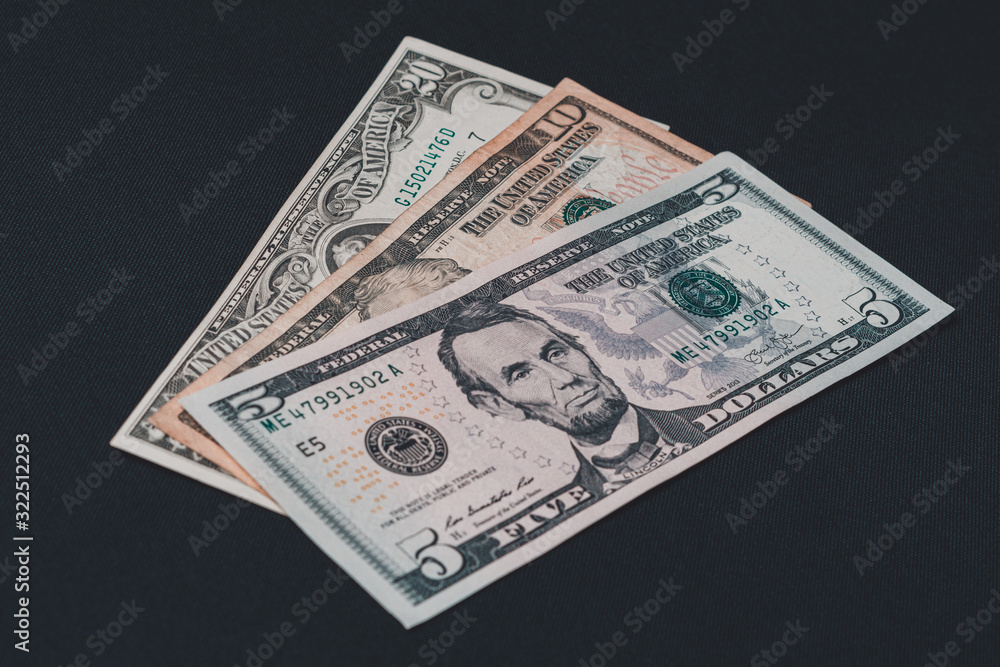 Five, ten and twenty dollar bills lie on a black background. Five, ten and twenty dollar bills lie on a black background.