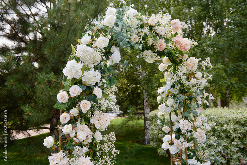 Fototapeta Naklejka Na Ścianę i Meble -  Beautiful wedding arch decorated with white and pink flowers in garden outdoors, copy space. Wedding setup. Place for ceremony. Floral composition