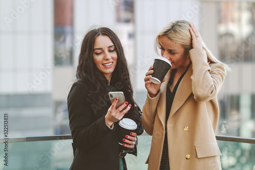 two women walk in the city, drink coffee and enjoy the rest