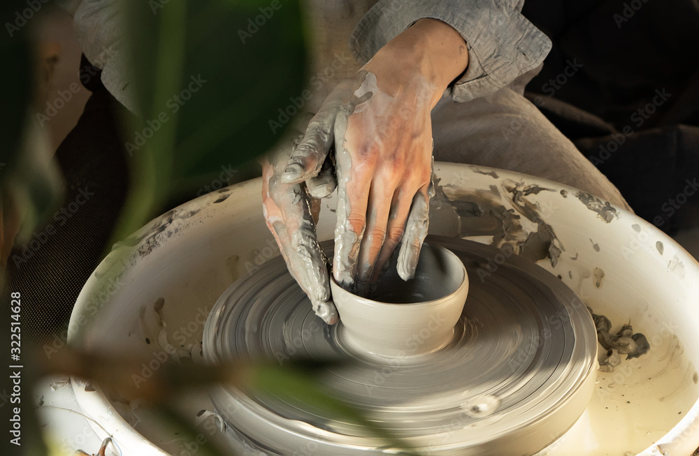 Fototapeta premium man potter making clay plate in pottery workshop