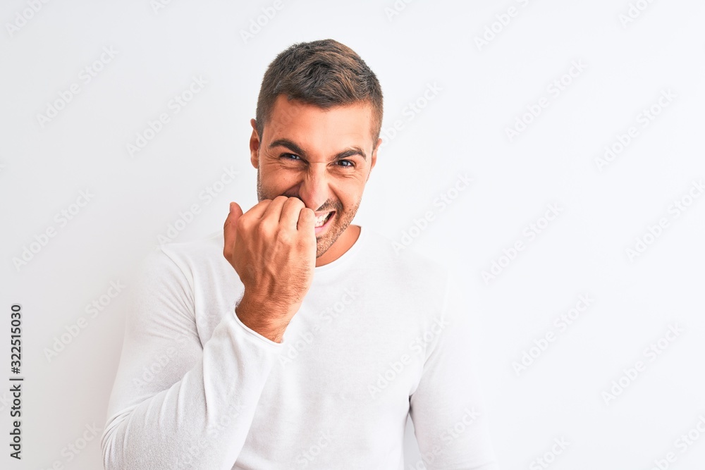 Young handsome man wearing white shirt over isolated background looking stressed and nervous with hands on mouth biting nails. Anxiety problem. Young handsome man wearing white shirt over isolated background looking stressed and nervous with hands on mouth biting nails. Anxiety problem.