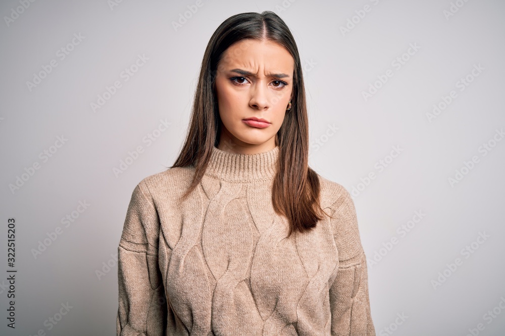 Young beautiful brunette woman wearing casual sweater standing over white background skeptic and nervous, frowning upset because of problem. Negative person.