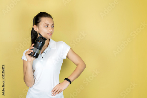 Beautiful young woman the brunette in white t-shirt with a fitness shaker drinking water. Sport fitness copy space