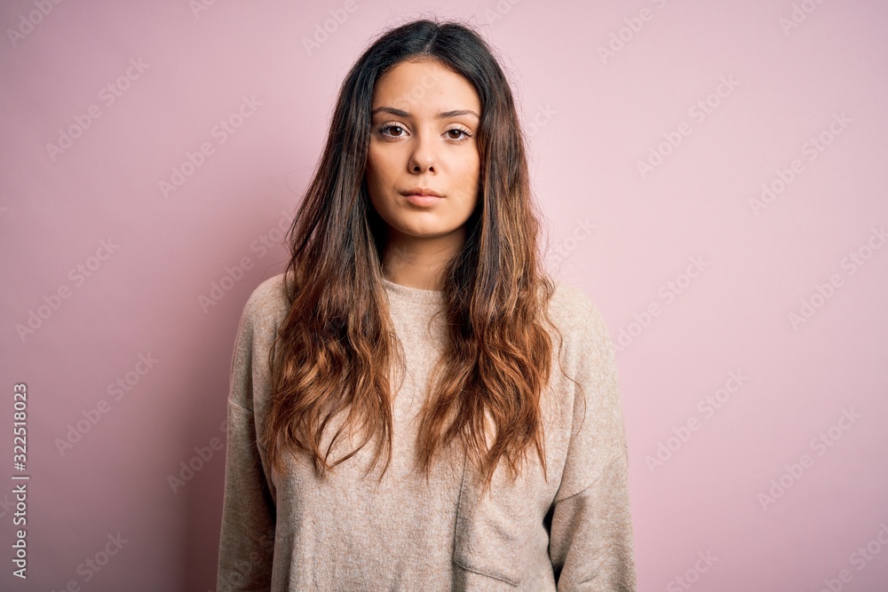 Young beautiful brunette woman wearing casual sweater standing over pink background Relaxed with serious expression on face. Simple and natural looking at the camera. Young beautiful brunette woman wearing casual sweater standing over pink background Relaxed with serious expression on face. Simple and natural looking at the camera.