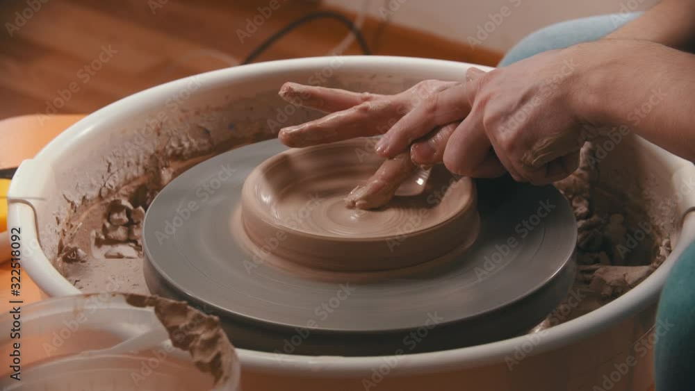 Pottery - master with finger is making the bottom for a clay bowl on the potter's wheel Pottery - master with finger is making the bottom for a clay bowl on the potter's wheel