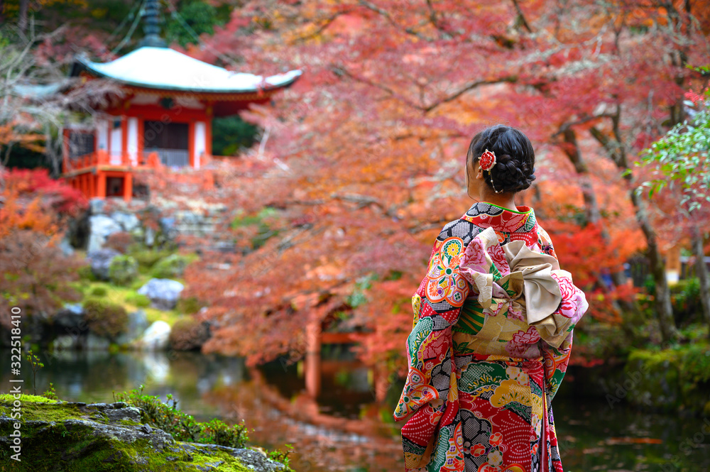 woman holding retro umbrella in old fashion style traditional kimono, sits in the middle of park of the village garden in autumn, travel and visit japan on incoming sport event