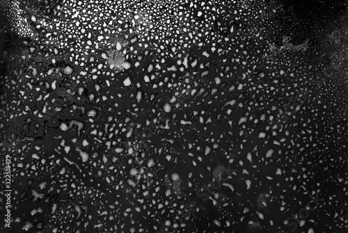 Texture of frozen glass. Wet cold glass on black background.