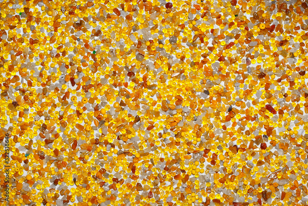 Texture of various jewels on a white background. Yellow, brown and orange stones. Beads and necklaces are glued to the wall. Texture of various jewels on a white background. Yellow, brown and orange stones. Beads and necklaces are glued to the wall.