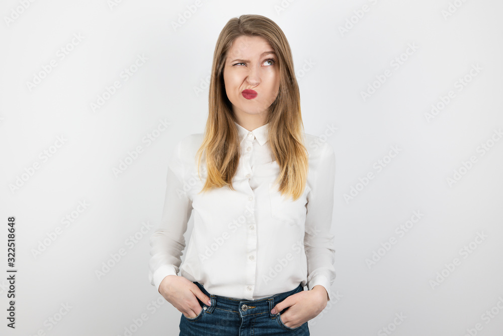 young beatuiful blond woman looks hesitant standing on isolated white background, body language young beatuiful blond woman looks hesitant standing on isolated white background, body language