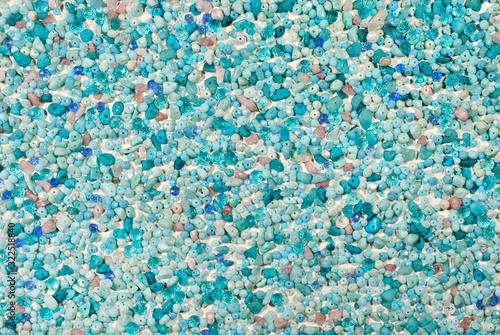 Texture of various jewels on a white background. Blue, purple, pink and cyan stones. Beads and necklaces are glued to the wall.
