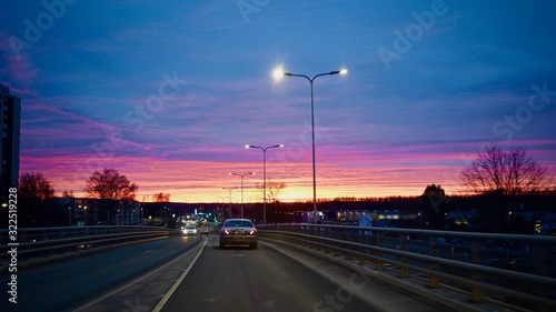 Beautiful colorful sunset in the city. Cars driving on the road during dawn. © roman