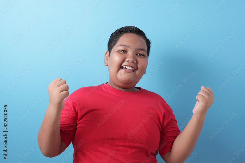 Happy success fat Asian boy shows winning gesture Happy success fat Asian boy shows winning gesture