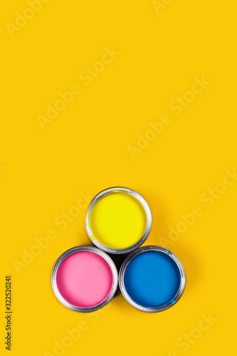 Renovation picture. Yellow background with three color paint cans. Flat lay, top view, copy space.