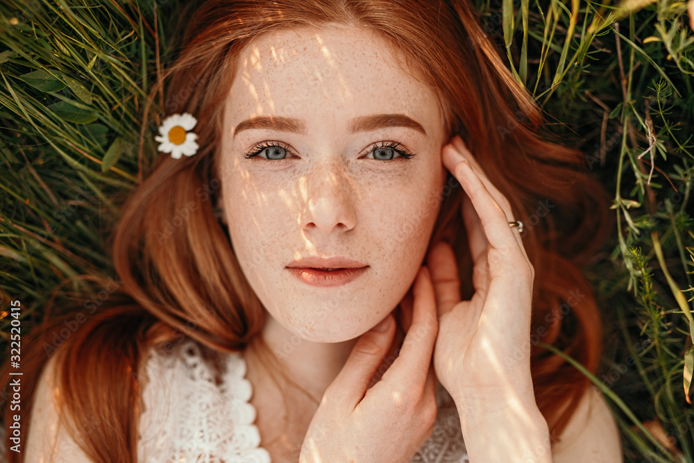 Redhead girl lying on green grass - obrazy, fototapety, plakaty 
