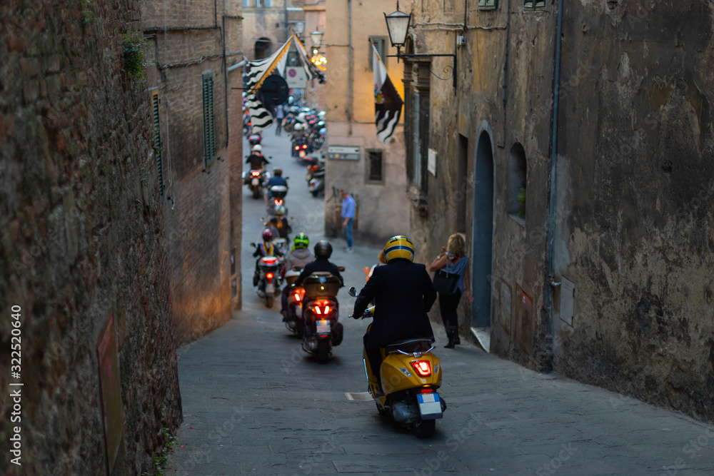 A line of scooters on a narrow street in Siena, Italy.