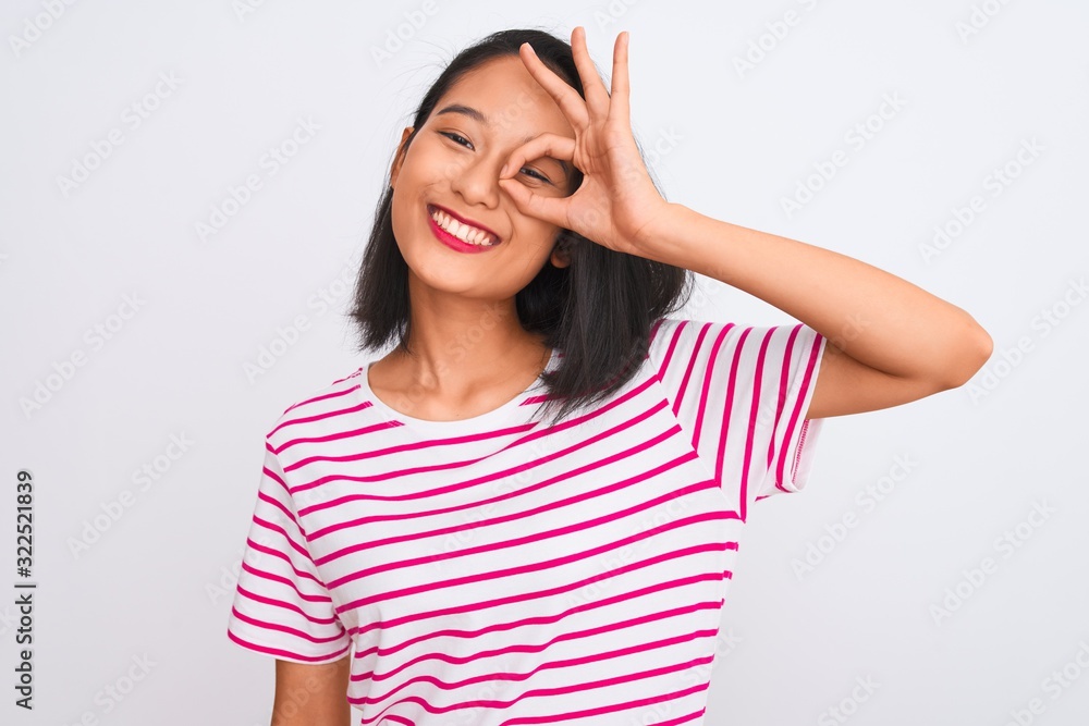 Young chinese woman wearing striped t-shirt standing over isolated white background doing ok gesture with hand smiling, eye looking through fingers with happy face. Young chinese woman wearing striped t-shirt standing over isolated white background doing ok gesture with hand smiling, eye looking through fingers with happy face.