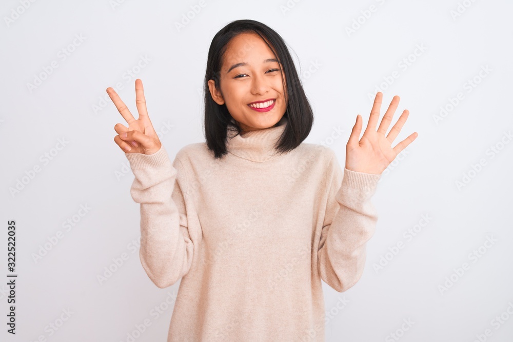 Young chinese woman wearing turtleneck sweater standing over isolated white background showing and pointing up with fingers number seven while smiling confident and happy. Young chinese woman wearing turtleneck sweater standing over isolated white background showing and pointing up with fingers number seven while smiling confident and happy.