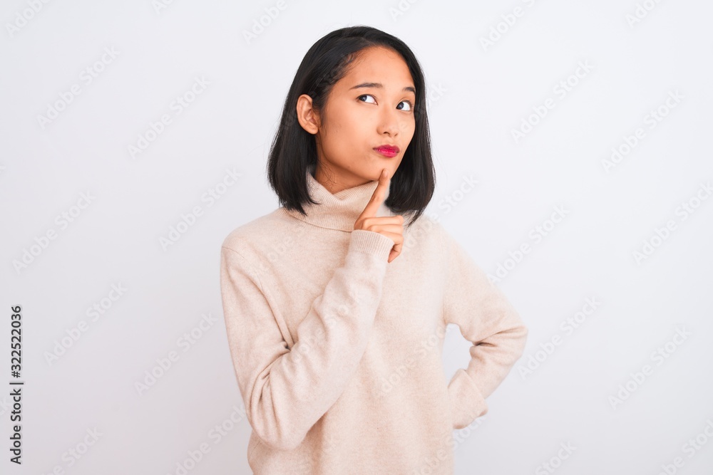 Young chinese woman wearing turtleneck sweater standing over isolated white background Thinking concentrated about doubt with finger on chin and looking up wondering Young chinese woman wearing turtleneck sweater standing over isolated white background Thinking concentrated about doubt with finger on chin and looking up wondering