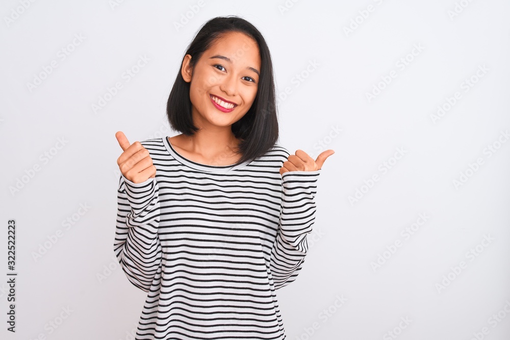 Young chinese woman wearing striped t-shirt standing over isolated white background success sign doing positive gesture with hand, thumbs up smiling and happy. Cheerful expression and winner gesture. Young chinese woman wearing striped t-shirt standing over isolated white background success sign doing positive gesture with hand, thumbs up smiling and happy. Cheerful expression and winner gesture.