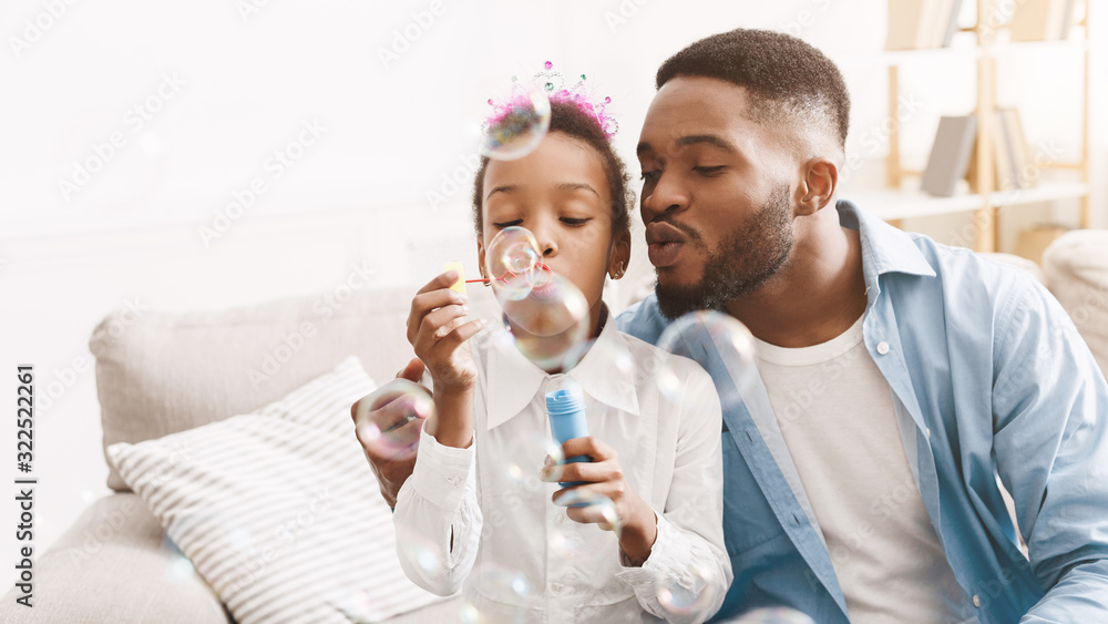 Handsome man spending time with daughter, blowing soap bubbles together Handsome man spending time with daughter, blowing soap bubbles together
