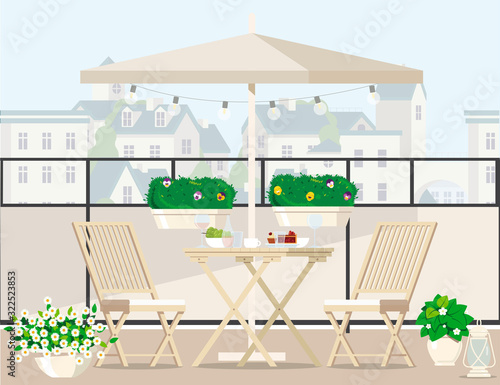 White garden furniture surrounded by plants on the balcony under an umbrella overlooking the city.