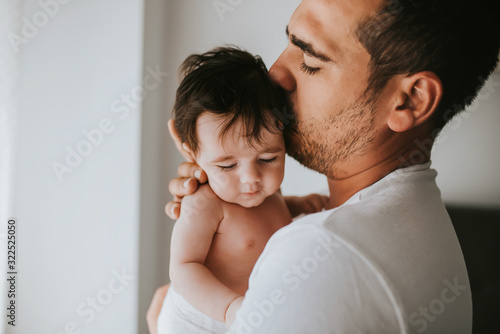 closed shot of father giving a kiss on the head of his baby - family