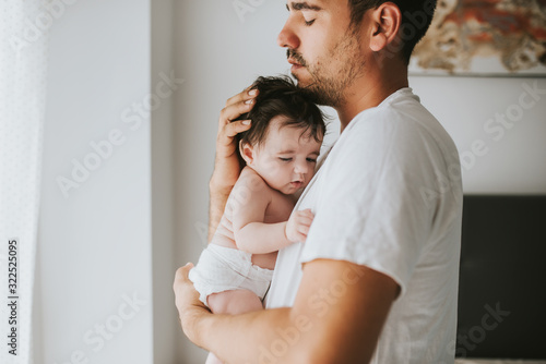 father with eyes closed hugging his baby