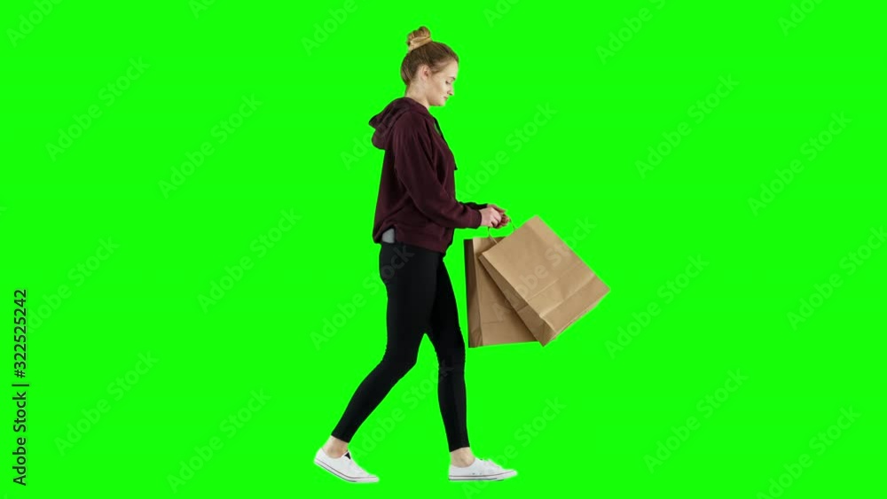 Casual Girl Talks on Her Phone Walking on Green Screen with Shopping Bags Casual Girl Talks on Her Phone Walking on Green Screen with Shopping Bags