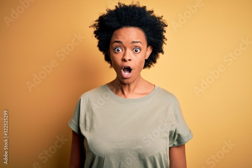 Young beautiful African American afro woman with curly hair wearing casual t-shirt afraid and shocked with surprise expression, fear and excited face. © Krakenimages.com