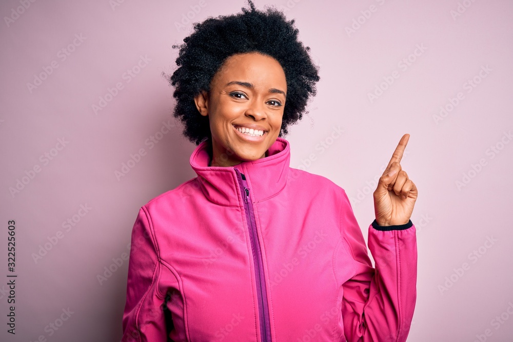 Young African American afro sportswoman with curly hair wearing sportswear doin sport with a big smile on face, pointing with hand and finger to the side looking at the camera. Young African American afro sportswoman with curly hair wearing sportswear doin sport with a big smile on face, pointing with hand and finger to the side looking at the camera.