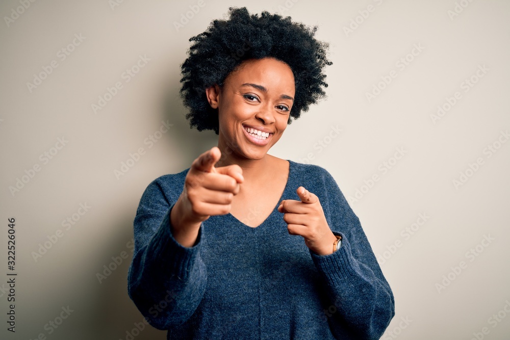 Young beautiful African American afro woman with curly hair wearing casual sweater pointing fingers to camera with happy and funny face. Good energy and vibes. Young beautiful African American afro woman with curly hair wearing casual sweater pointing fingers to camera with happy and funny face. Good energy and vibes.