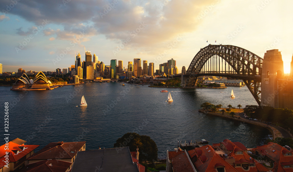 Obraz premium Punkt widokowy na port w Sydney z miastem i mostem w czasie zachodu słońca