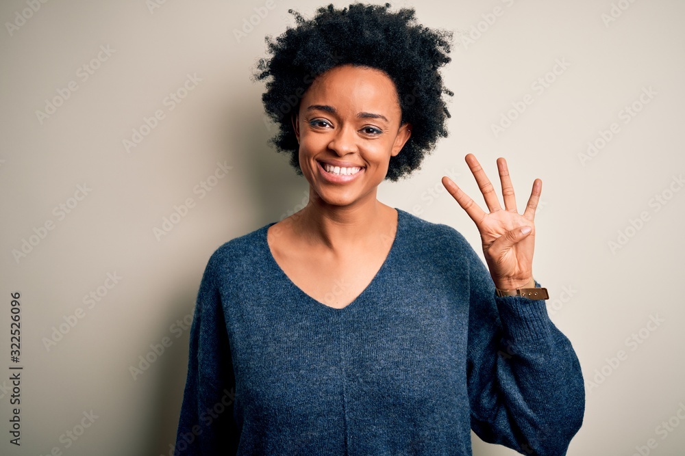 Young beautiful African American afro woman with curly hair wearing casual sweater showing and pointing up with fingers number four while smiling confident and happy. Young beautiful African American afro woman with curly hair wearing casual sweater showing and pointing up with fingers number four while smiling confident and happy.