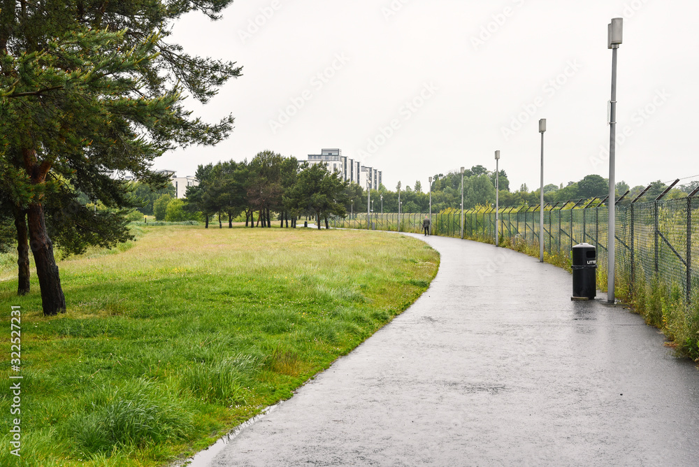 Path lined with a fence and street lights in a public park