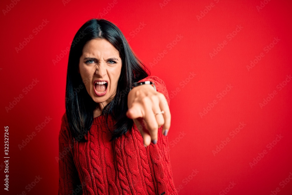 Young brunette woman with blue eyes wearing casual sweater over isolated red background pointing displeased and frustrated to the camera, angry and furious with you Young brunette woman with blue eyes wearing casual sweater over isolated red background pointing displeased and frustrated to the camera, angry and furious with you