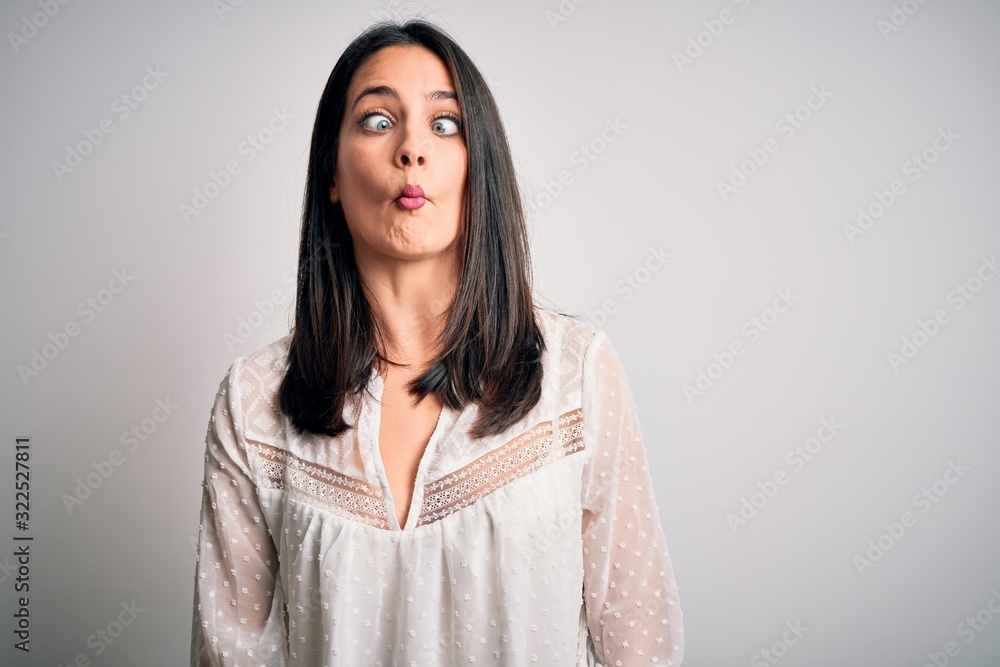 Young brunette woman with blue eyes wearing casual t-shirt over isolated white background making fish face with lips, crazy and comical gesture. Funny expression. Young brunette woman with blue eyes wearing casual t-shirt over isolated white background making fish face with lips, crazy and comical gesture. Funny expression.